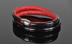 Armbånd i sort lak læder og rød kalveskind. 2 omgange med magnetlås i stål. Tykkelse 7,5 mm.